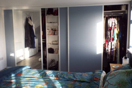 Long, grey wardrobe opened with clothes