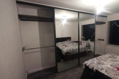Mirrored wardrobe in white bedroom, left side open