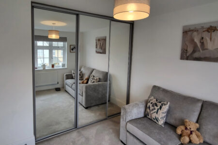 Mirrored wardrobe in room with grey sofa