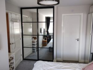 A well-decorated bedroom with a chic two-door black sliding wardrobe.