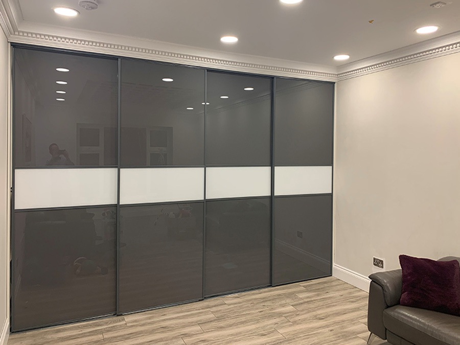 Interior view of a room with a couch and a four door glass sliding wardrobe, creating a stylish and open atmosphere.