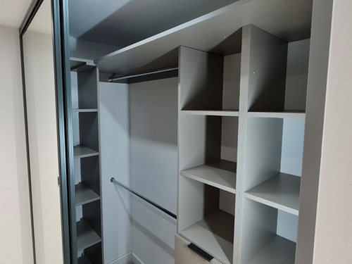 Empty walk-in closet with grey shelves and hanging rail wardrobe interiors. 