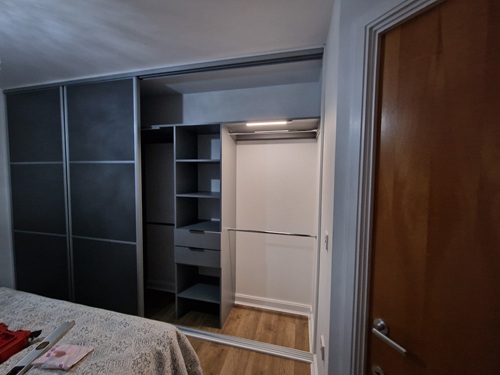 Modern sliding wardrobe featuring bright internal LED lighting for enhanced visibility.