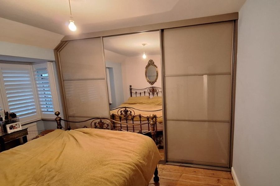 Angled sliding wardrobe installed beneath a sloped ceiling